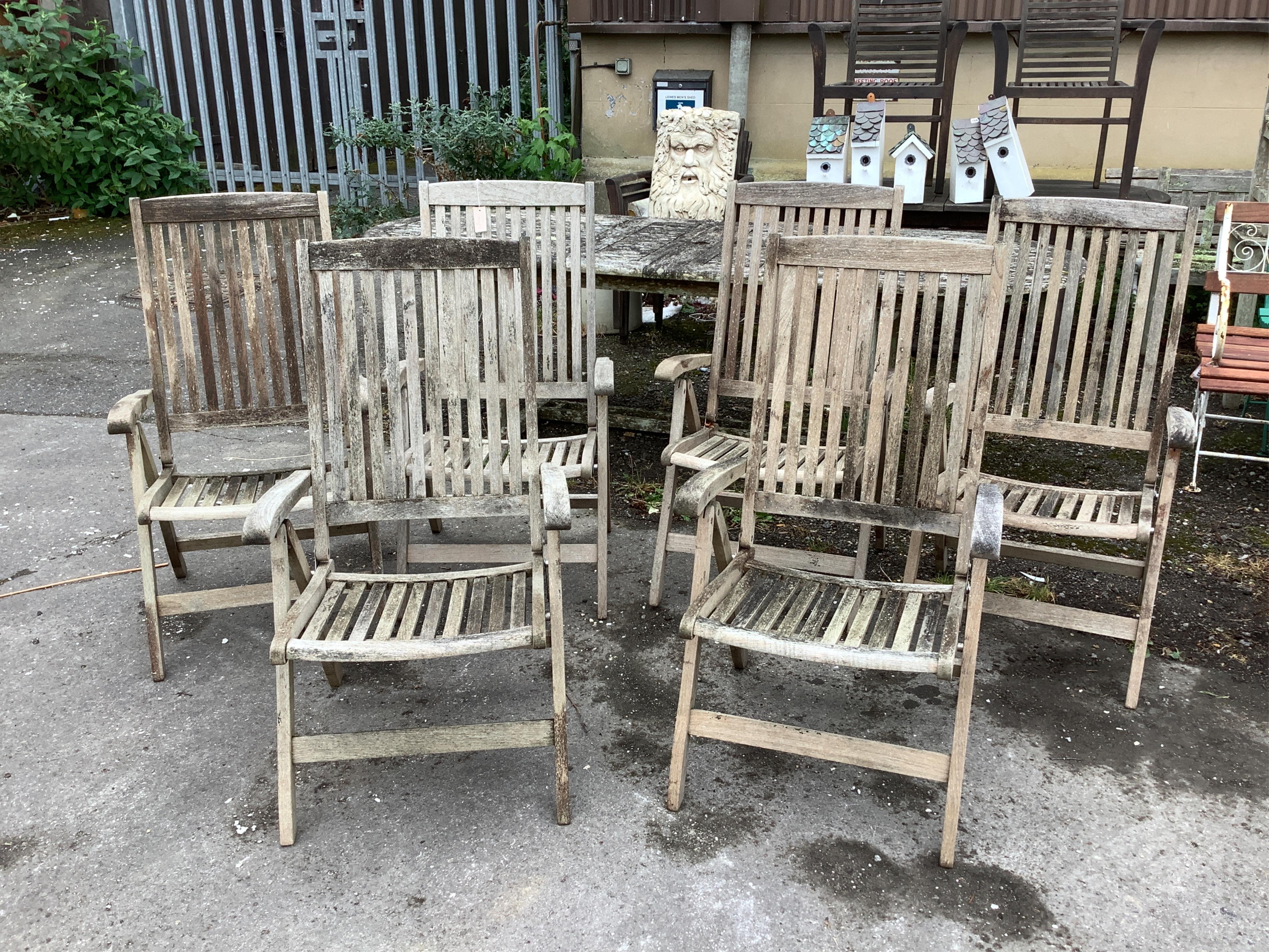 A weathered teak oval extending garden table, width 239cm extended, depth 109cm, height 73cm together with six Neptune weathered teak folding reclining garden armchairs with five Neptune cushions